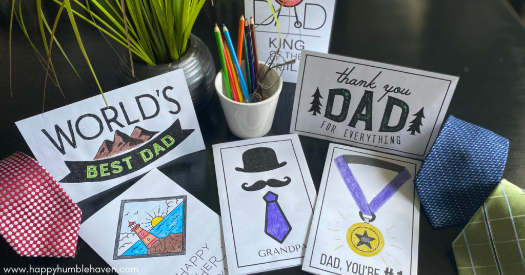 Collage of all 6 Printable Father's Day cards laying on a table with a plant and container of colored pencils.